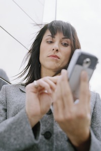 Business woman standing outside in front of office building, using mobile phone
