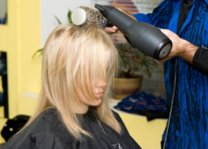 Barber makes a hair-dress to the young blonde