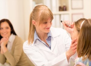 Female pediatrician doing eye check-up to little girl