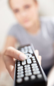 Young woman with remote watching TV.