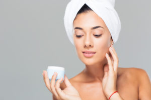 Woman with towel on head holding cream jar