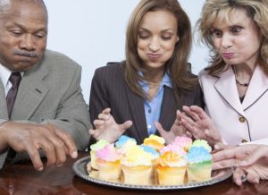 Businesspeople eating cupcakes in office