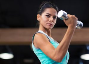 Portrait of a charming woman workout with dumbbells in fitness gym