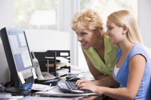 Woman and girl in home office with computer smiling