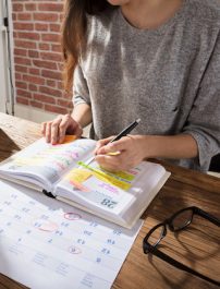 Close-up Of A Businesswoman Making Agenda On Personal Organizer At Workplace