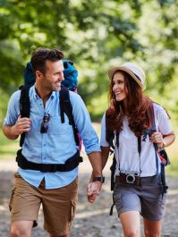 Happy couple hiking together in mountains with backpacks