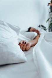 woman sleeping in bed hand close up selective focus white sheets